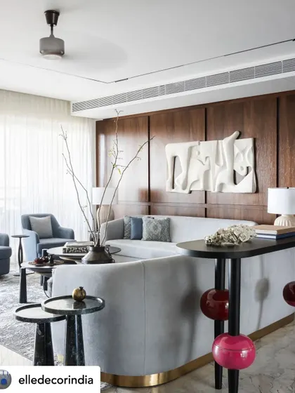 A striking 3D wall mural in white brings this living room to life, its abstract forms playing with light and shadow. The powder blue sofa and unique side table with fuchsia pink spheres create a conversation-starting contrast.