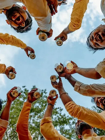 A low-angle shot of the groom's friends toasting to his happiness during the Haldi party.