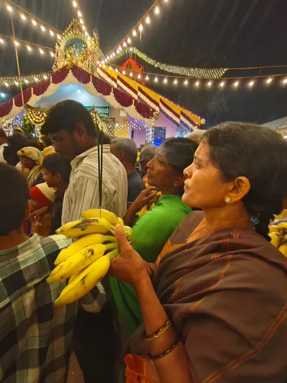 A devotee holding bananas as an offering, waiting for the deities to pass during the jatre.