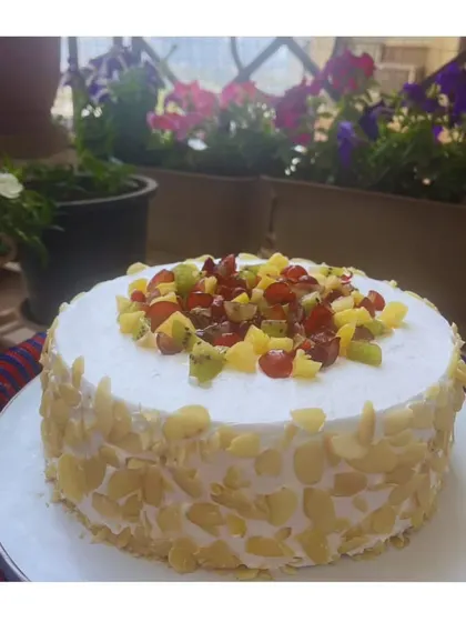 My fresh fruit cake is a celebration of summer. Topped with a colorful medley of seasonal fruits like kiwi, grapes, and pineapple, and coated with crunchy almonds, it's as beautiful as it is delicious.