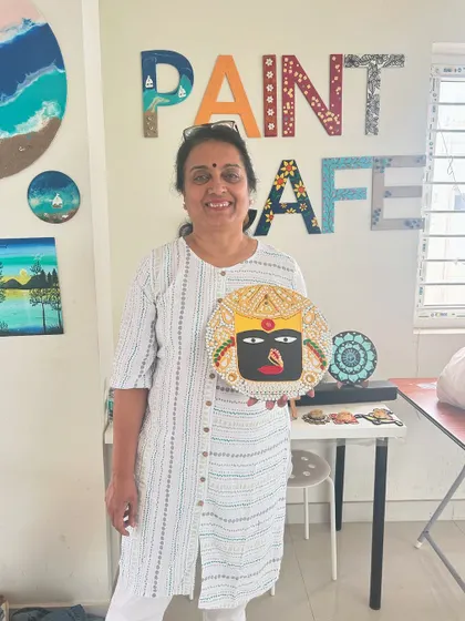 A participant with her unique Lippan art piece featuring a traditional mask design.