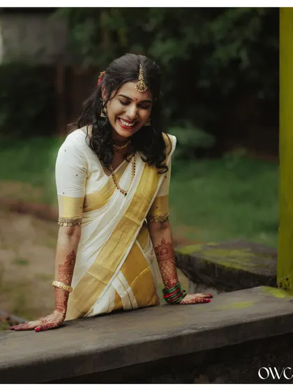 A joyful, candid shot of the bride laughing, dressed in her elegant kasavu saree.