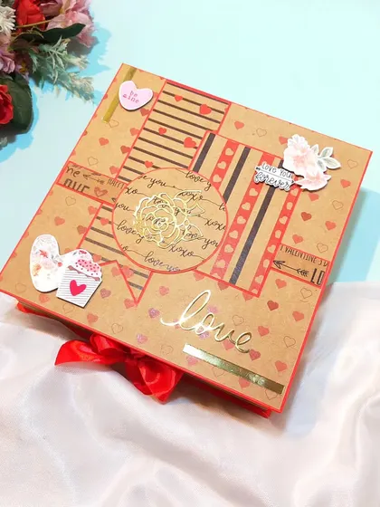 The cover of the love-themed scrapbook, tied with a red ribbon.