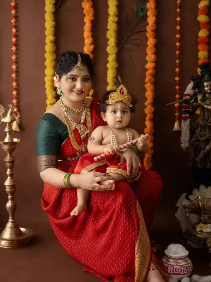 A beautiful portrait of mother and child, with the baby holding his flute, ready to celebrate Janmashtami.