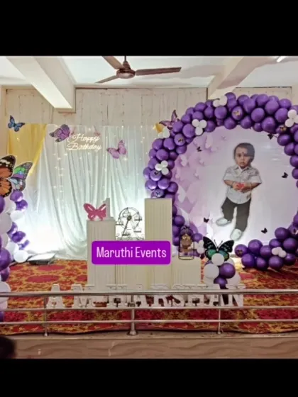 A personalized butterfly theme featuring a photo of the birthday boy inside the circular backdrop. The purple and white balloon decor adds an elegant touch.