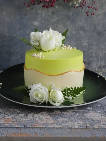 This elegant fault line cake features a refreshing lime green glaze and is decorated with beautiful fresh white roses, making it a perfect choice for anniversaries, engagements, or sophisticated parties.