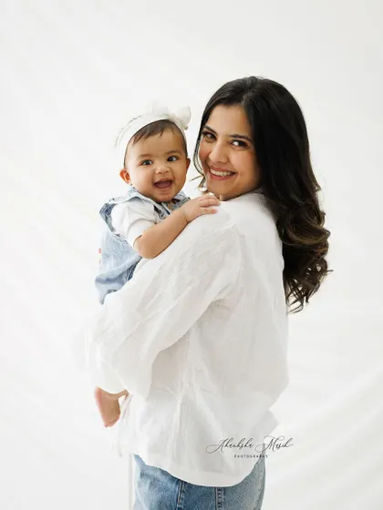 A close-up portrait capturing the sweet and happy bond between a mother and her baby. The baby's bright smile is the heart of this image.