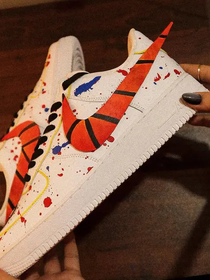 Holding up the basketball-themed AF1. The custom-painted swoosh is the star of the show, designed to look like the textured surface of a basketball.
