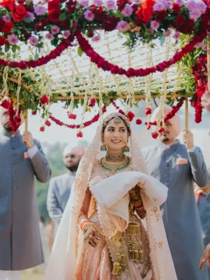 The bride makes her graceful entrance under a beautiful 'phoolon ki chaadar'. We custom design these floral canopies to complement the bride's attire and the overall wedding theme, adding a personal touch to this cherished tradition.