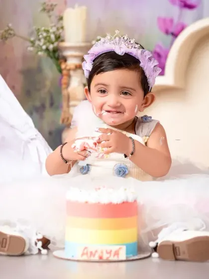 Getting the first taste of her rainbow birthday cake! This cake smash photo captures the messy, fun, and delicious part of the celebration.