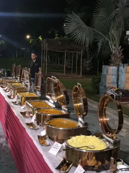 A full dinner spread ready for an evening event in a garden setting. The buffet includes a variety of main courses, rice, and breads, all kept warm in our high-quality copper chafing dishes.