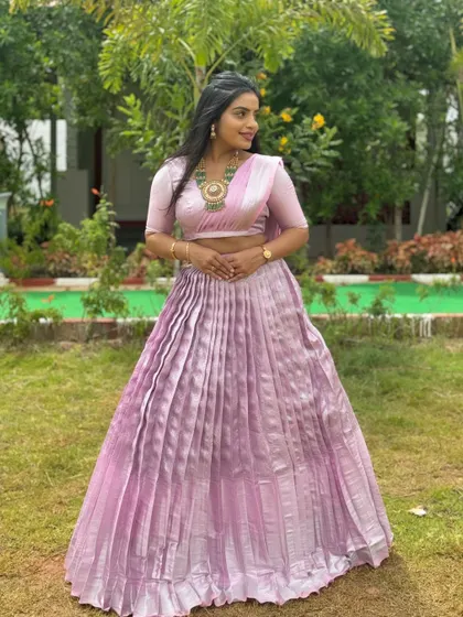 The lavender Langa Dhawani seen from another angle, highlighting the shimmer of the pleated skirt in a garden setting.