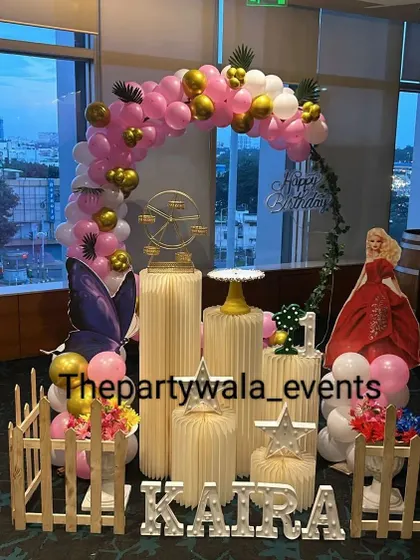 A unique take on a princess theme with a Barbie cutout and a butterfly accent. The pink and gold balloon arch is set against a window, creating a beautiful silhouette effect.