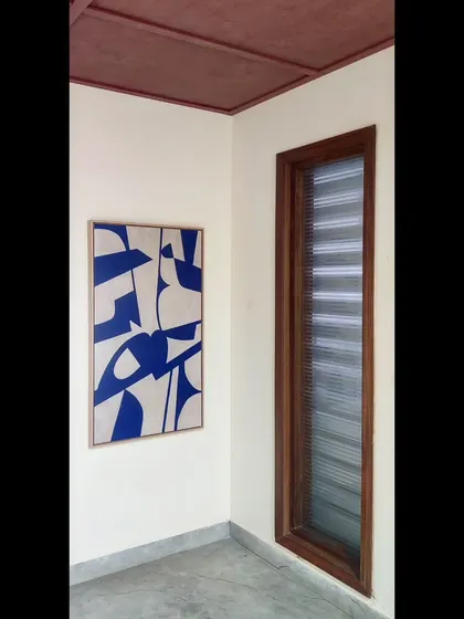 Another view of the bold blue and white abstract painting, showing how it commands attention in a corner space. Its vertical orientation is perfect for adding height and interest to a room.