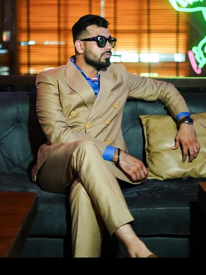 A relaxed moment in our beige double-breasted suit. The vibrant blue shirt underneath adds a pop of color, showcasing how to style a neutral suit for a more contemporary, casual feel.