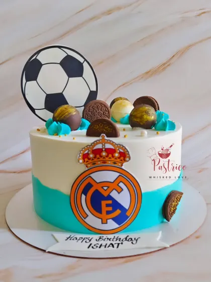 A Real Madrid football-themed cake for a true fan, featuring the team's logo and a soccer ball topper.