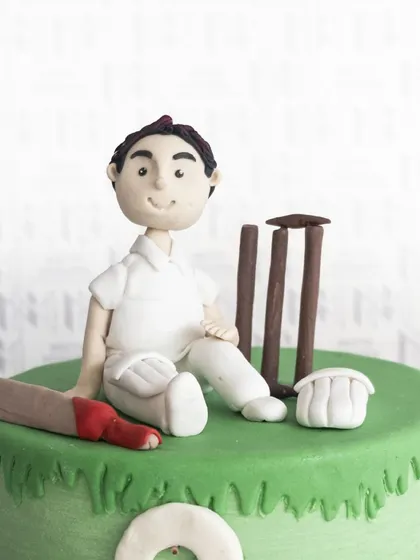 A close-up of the hand-sculpted cricketer, complete with a bat, wickets, and pads.