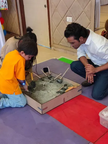 An instructor guides a young paleontologist at our fossil excavation station, a sensory activity where kids dig for hidden treasures.