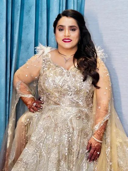 Sparkle, shine, and slay the day. This bridal reception look is all about glamour, with a bold red lip and radiant skin that complements her sparkling gown.