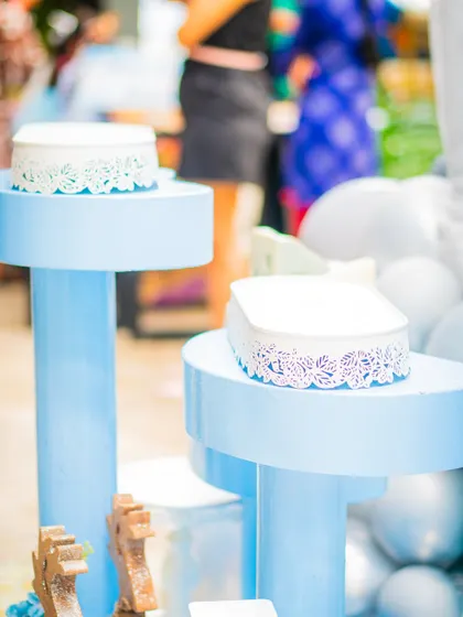 A detail shot of the decor, featuring light blue pedestals with delicate lace-like trim, used to display cakes or other party elements.