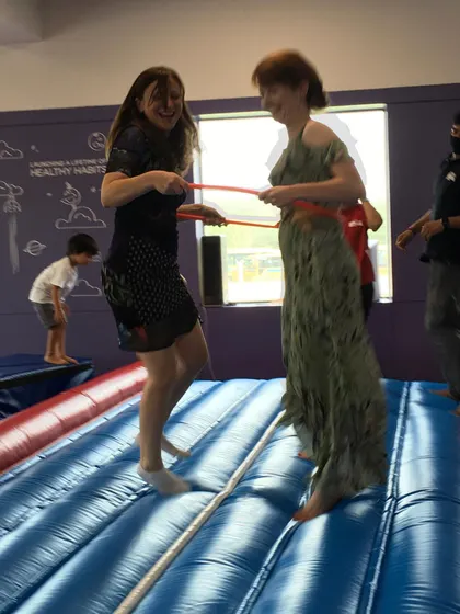 Even the adults can't resist the fun! Two moms enjoy a laugh while trying out a game on the Air Track during a birthday party.