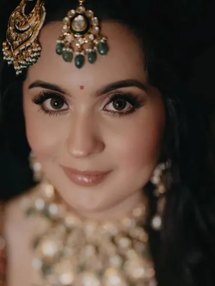 A beautiful close-up of the bride, showcasing her flawless makeup, sparkling polki and emerald jewelry, and the delicate details of her maang tikka and pasha.