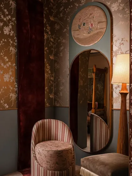 Welcome to Zone Two, a space inspired by the softness and intricacy of a boudoir. Here, a custom mirror with an embroidered panel sits beside a striped chair and a unique wall rug that appears to spill onto the floor, creating a sense of movement.
