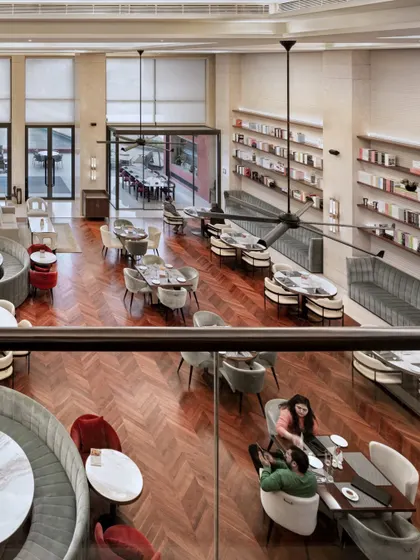 This high-angle view of the Elevate Clubhouse in Gurugram captures the essence of my design approach. The double-height ceiling and open layout create a sense of grandeur, while the distinct seating zones, rich herringbone flooring, and warm lighting foster a welcoming atmosphere for community interaction.