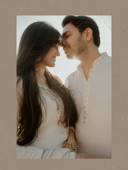 A close-up, sunlit portrait of a couple, their faces close together. The warm light and their gentle smiles create an image full of intimacy and affection.