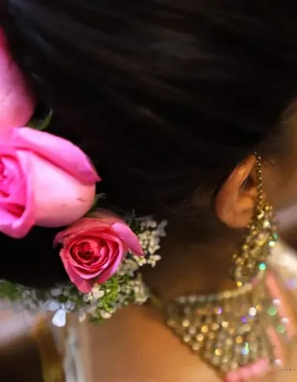 A close-up of a bride's beautiful hair bun, adorned with fresh pink roses.