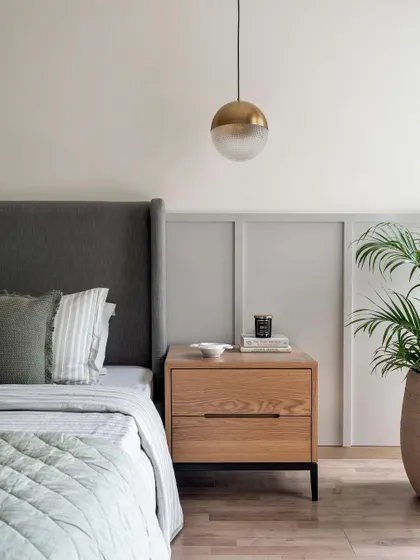 This bedroom uses a soft grey-green on the lower half of the wall, paired with a simple upholstered headboard and light wood nightstand. It's a perfect example of creating a calm space with subtle color.