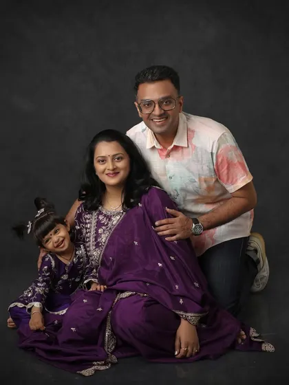 A happy family portrait with everyone dressed in shades of purple. I love coordinating outfits to create a cohesive and visually stunning family photograph against a classic backdrop.