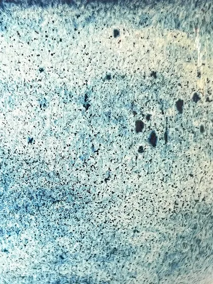 A macro shot of the beautiful, speckled blue glaze on the ceramic goblet.