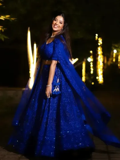 A full-length shot of the royal blue engagement lehenga. The makeup is designed to be impactful both up close and from a distance, ensuring the bride looks stunning in all her event photos.