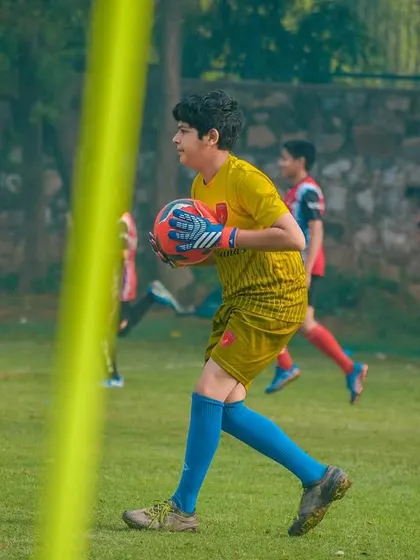 A goalkeeper confidently claims the ball, ready to start a new attack from the back.