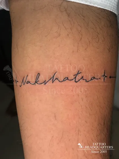 The name "Nakshatra" written in a delicate script that forms a line across the arm.