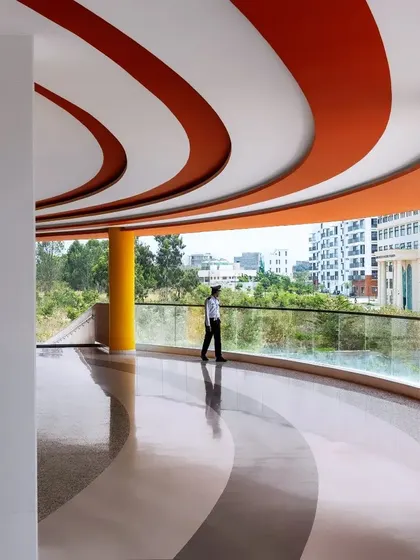 The curved corridors of the MARC Auditorium offer expansive views of the campus. The design uses bold color and form to guide movement and create visual relationships between the interior and the exterior landscape.