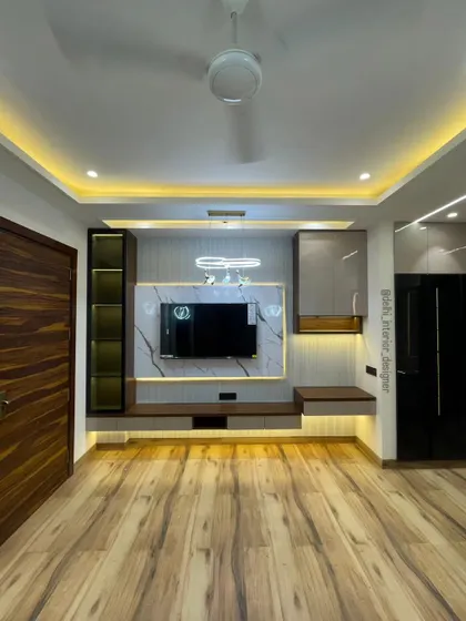 A full view of the bedroom, showing the wooden flooring and the TV unit. The design creates a warm and cozy environment, perfect for relaxing.