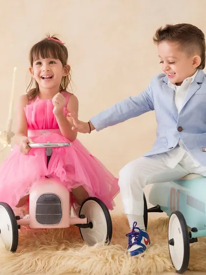 A fun, interactive moment between siblings as they play together on their toy cars, sharing a laugh.