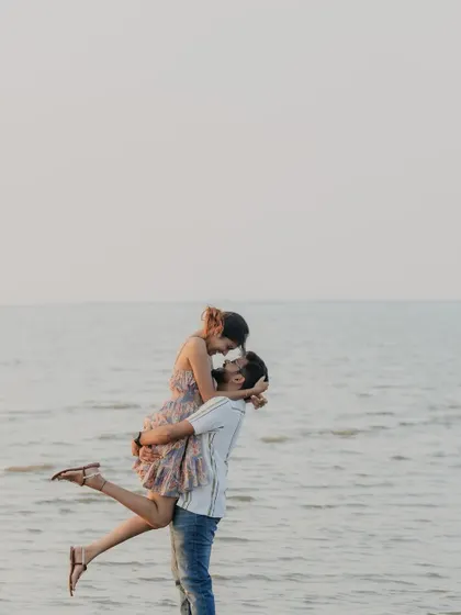 A classic, joyful lift against the open sea at sunset. This image captures a moment of pure happiness and romance, celebrating the start of a new journey together.