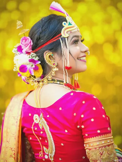 A profile shot of the bride showing off her hairstyle, adorned with fresh flowers, and the detailed embroidery on her blouse.