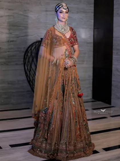 A full-length portrait of a bride in a magnificent multi-colored lehenga with earthy tones. The modern, minimalist background makes the intricate outfit the star of the show.