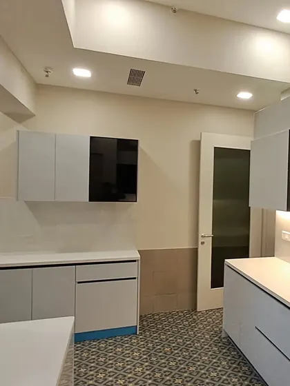 A wide-angle view of the completed Paras Quartier kitchen, showing the spacious layout, patterned flooring, and the seamless integration of the cabinets and countertops.