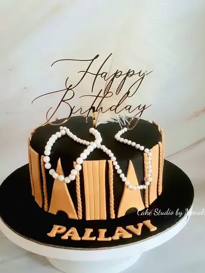 A Great Gatsby themed cake in black and gold. The design is inspired by the art deco style of the 1920s, with pearls and feathers for a touch of glamour.