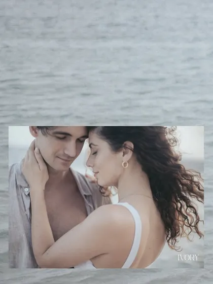An intimate close-up of a couple sharing a tender moment, framed against the soft texture of the ocean waves. This artistic composition highlights their gentle connection and the serene beauty of their Bali pre-wedding shoot.