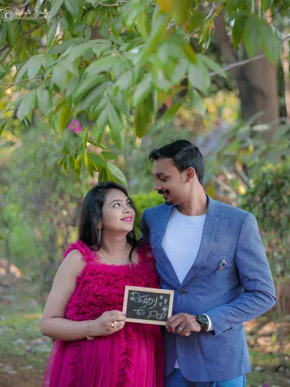 The couple looks at each other with smiles as they hold a sign announcing their excitement. It's a sweet and simple way to add personality to your photos.