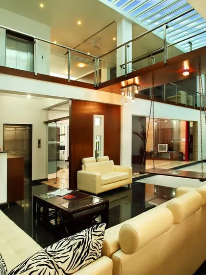 The central living area of a modern courtyard home, designed to be the heart of the residence. The double-height space, skylight, and glass walls create a seamless visual connection between floors and flood the interior with natural light.