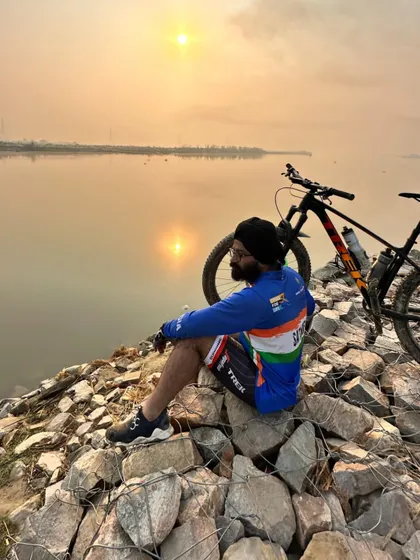A cyclist enjoying a moment of solitude by the water at sunrise. These are the peaceful moments that make early morning rides so special.