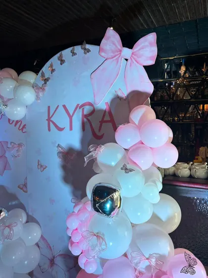 A close-up of the custom backdrop for Kyra's half-birthday, featuring a large pink bow and her name in a beautiful script.