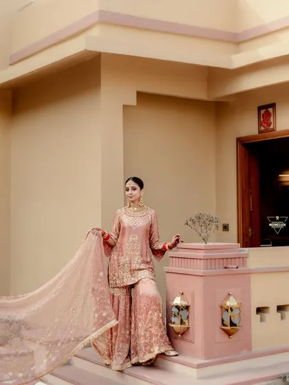 The bride in her stunning pink sharara, her flowing dupatta adding a touch of drama and elegance to this beautiful portrait.
